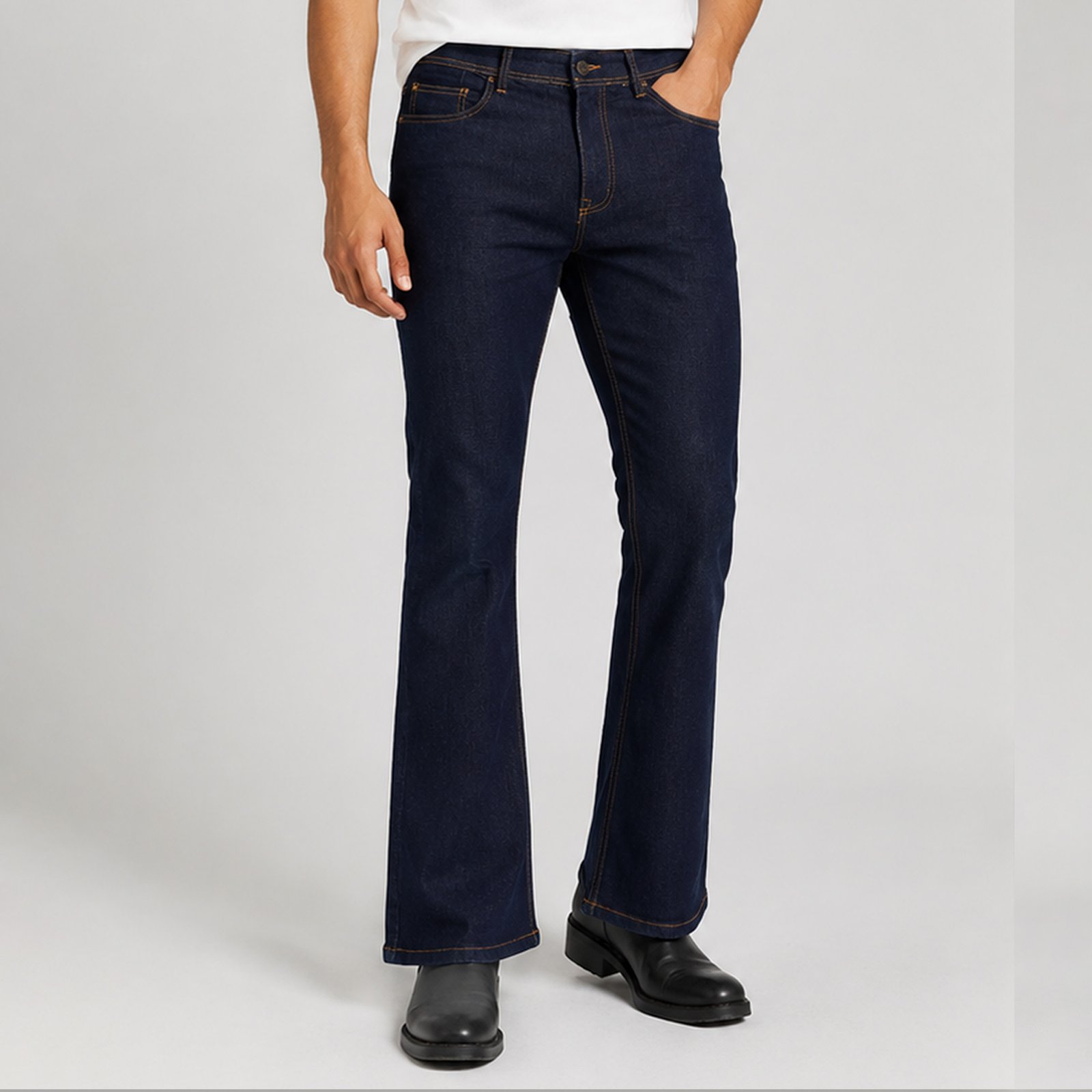 A male fashion model stands in a clean studio setting wearing dark indigo bootcut jeans, a fitted white crew-neck T-shirt, black leather boots, and black sunglasses. The main image shows a full-body front view highlighting the slim thigh fit and gradual flare from the knee to the hem. Three smaller panels on the right display additional product details: a front view of the jeans, a back view showing the rear pockets and waistband patch, and a close-up of the front pocket area with contrast tobacco stitching. The jeans feature a dark rinse wash, classic five-pocket styling, and a bootcut silhouette designed to fit over footwear. The background is neutral light gray, creating a professional e-commerce presentation.
