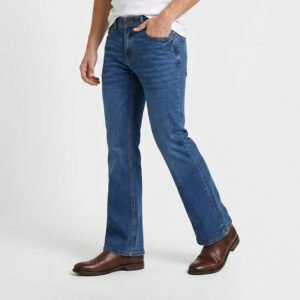 Male model showcasing Mid Blue Bootcut Jeans in a front walking pose, paired with brown leather Chelsea boots to highlight the premium flare and tailored thigh.